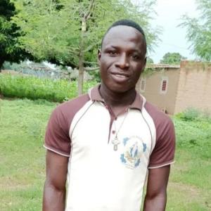 Eric in a white and brown polo shirt, standing outside