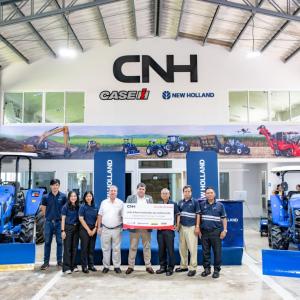 A group posed, some holding a large check, in a CNH showroom.