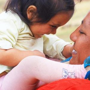 Adult holding a small child close to them, face to face