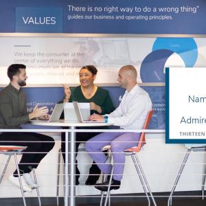 Three people seated at a table in discussion, smiling. Each has a laptop open. "Whirlpool Named one of the world's most admired companies" on the right side.