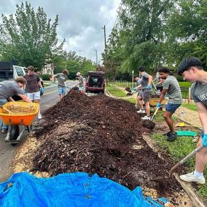 Volunteers shoveling mulch.