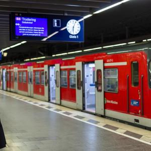 a person waiting on an underground train platform, a train with open doors in front of them