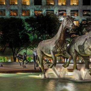 Large outdoor statues of three horses splashing in a water feature.