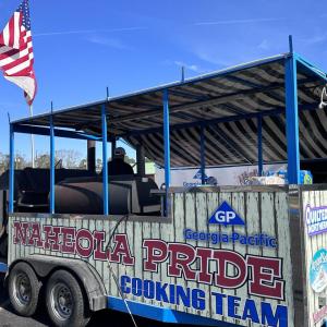 Cooking trailer with open sides and "Naheola Pride cooking team" on the side with Georgia-Pacific logo