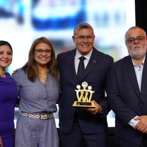Four people posing, one holding an award