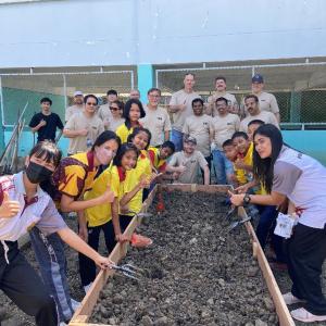 A team of people posed by a raised garden bed.