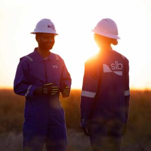 Two SLB workers talking with the sun setting behind them