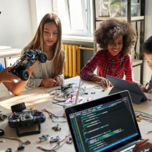 Young people work at a table on computers and electronics