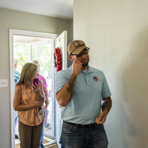 Sgt. David Long wipes a tear as he and another person enter the home