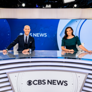 Two anchors behind a CBS News desk