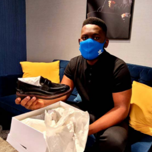 a person opens a show box holding a new black shiny work loafer