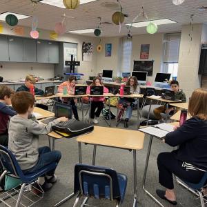 Karen Braun and students at desks in a circle in a classroom.