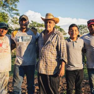 A group of five farmers with arms around each other.
