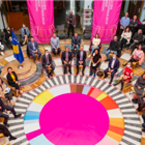 aerial shot of a large group of people sitting around a pink circle in a rotunda. Banners hanging from the second floor.
