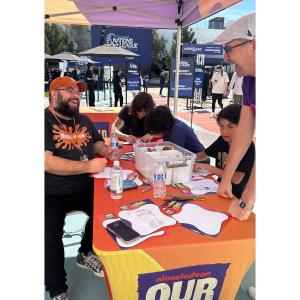 People sitting at a colorful table underneath a tent