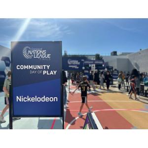 Sign "Concacaf Nations League Finals Community Day of Play, Nickelodeon" in foreground in front of children doing activities