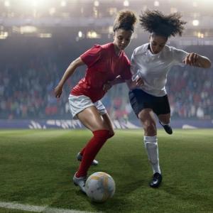 Female soccer players competing for the ball in a game.