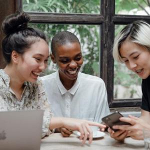 Three female influencers seated at a table in front of a laptop.