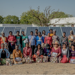 Villagers in bright clothes in front of a solar array
