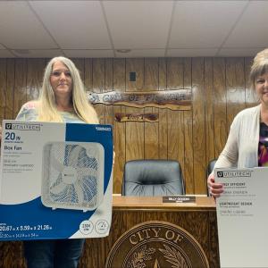 Three people in an office setting holding box fans.