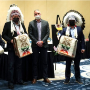 a group of five people, four wearing native american head coverings and carry woven blankets
