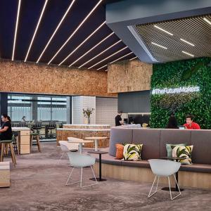 An open space with chairs, benches, carpeted floors, a wall of greenery.