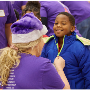 An adult helps a child zip a coat on.