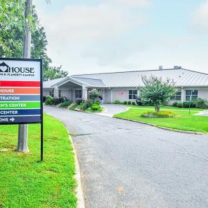 A single-story building "Our House" sign in front with arrows pointing to different buildings.