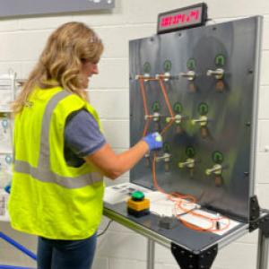 Teacher in yellow vest at a station
