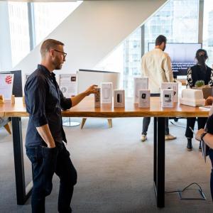 A person explaining to others, pointing to boxes for products.