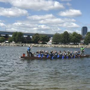 A group in a long boat paddling on a body of water.