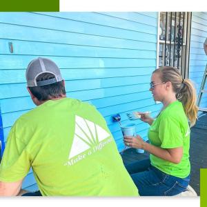 Volunteers painting the exterior of a home blue.
