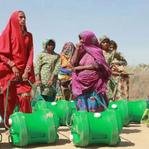 a group of people each with a large green water jug