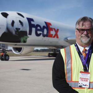 Dave Lange standing outside in front of a FedEx plane with a panda on the side.