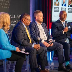 Four people with microphones seated on a stage