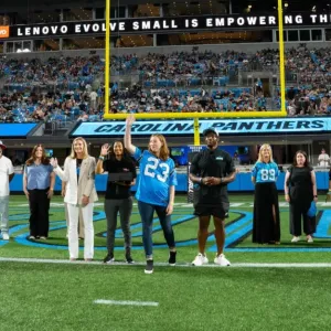 A line of people waving on a football field.
