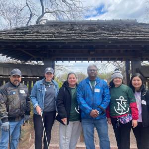 A group posed with trash pickers in a park setting.