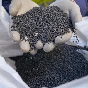 Two hands holding small plastic pellets.