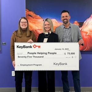 Three people holding an oversized check from KeyBank