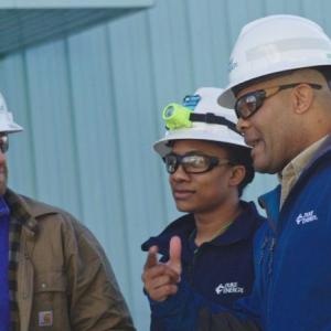 Derrick Smith with two others in hard hats, talking outside a building.