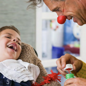 man in a clown nose visiting a disabled child