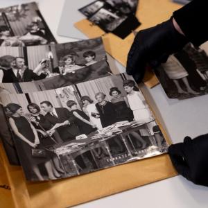 Gloved hands holding a black and white photo.