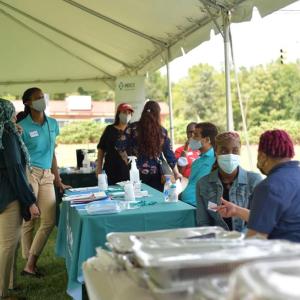 under an outdoor tent a group of people mingle
