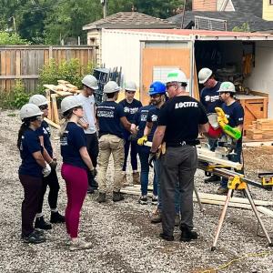 Volunteers outside a home being built, working with wood.