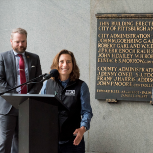 Spokesperson at a podium, two others behind them