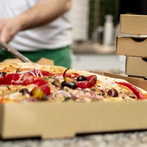 A person placing a pizza in a box.