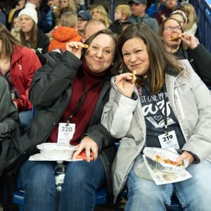 Two people in the crowd eating pizza