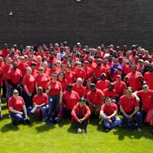 A large group posed outside in matching orange shirts.