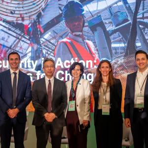 Tracey Campbell and four others posed in front of a large display on a stage.