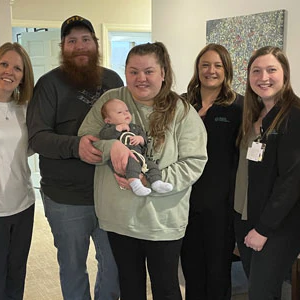 A group of people around a mother and baby